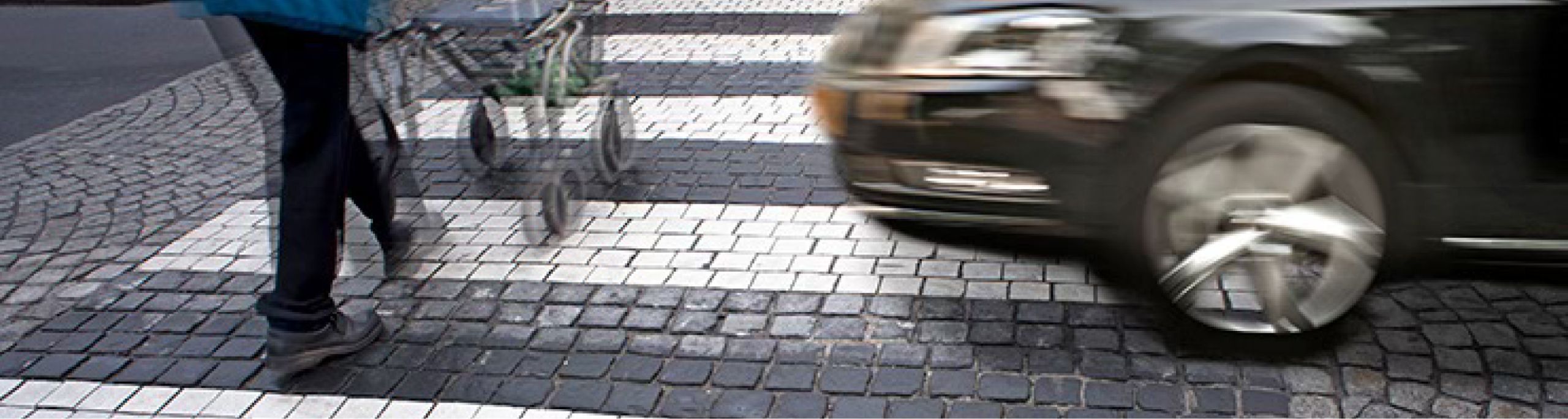 A pedestrian about to be hit by a moving car while walking through a crosswalk